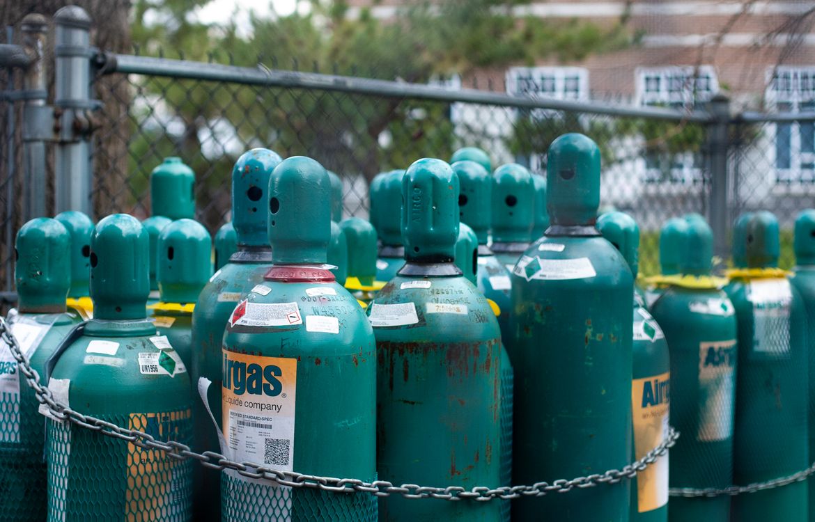 Industrial gas cylinders chained upright in a secure outdoor storage area